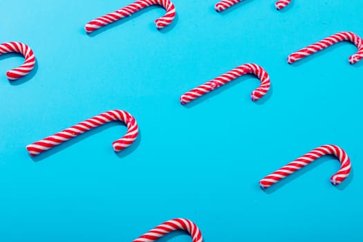 Composition of rows of multiple candy canes on blue background. christmas, tradition and celebration concept.