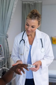 Caucasian female doctor attaching pulse oximeter on male patient finger. medicine, health and healthcare services.