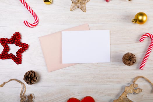 Composition of white card with copy space, envelope and christmas decorations on wooden background. christmas, tradition and celebration concept.