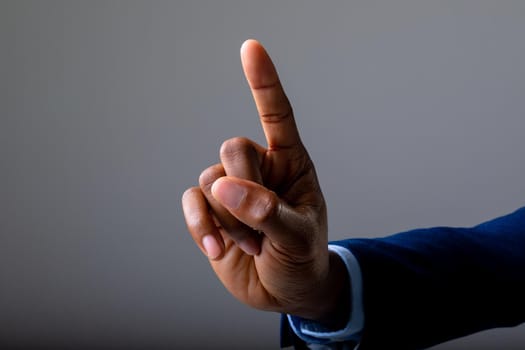 Close up of hand of businessman touching invisible screen against grey background. business, professionalism and technology concept