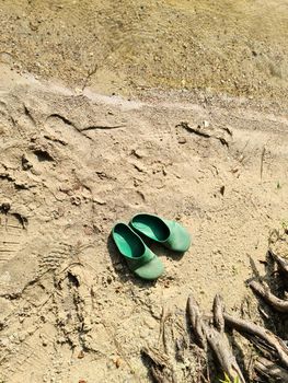 A pair of abandoned flip flops in the sand at a lake