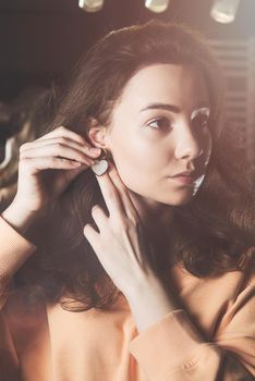 close up of beautiful young woman puts on heart shaped earrings