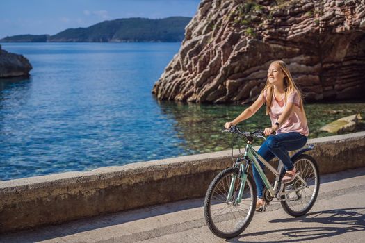 Woman tourist on a bicycle explores Budva in Montenegro. Cycling in Montenegro concept.