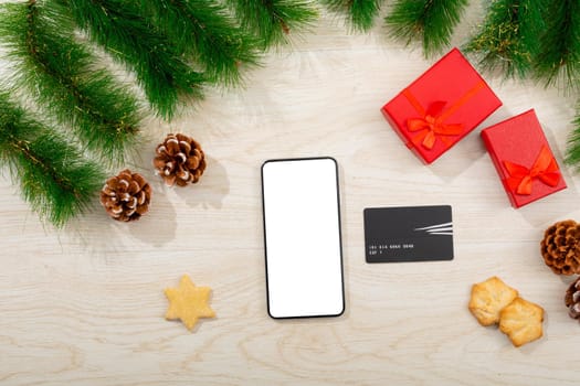 Composition of smartphone with copy space, card and christmas decorations on wooden background. christmas, communication, tradition and celebration concept.