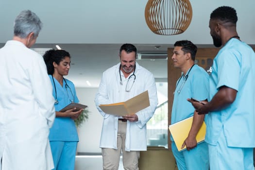 Diverse male and female doctors standing in hospital corridor and discussing. medicine, health and healthcare services.