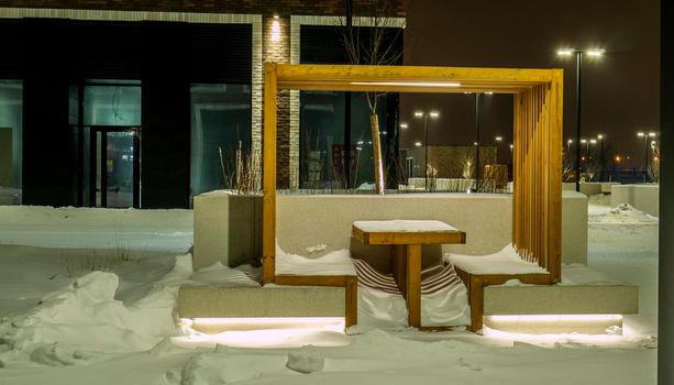 Benches and tables are covered with snow after a winter storm in the courtyard of a house in Moscow. evening shooting. color