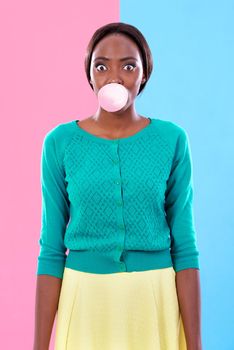 Studio shot of an attractive young woman blowing a gum bubble against a colorful background.