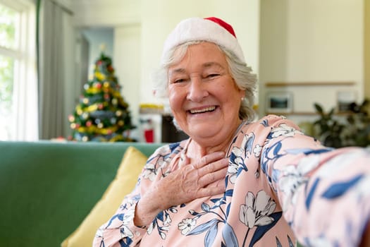 Happy caucasian senior woman wearing santa hat having video call at christmas time. christmas, festivity and communication technology.