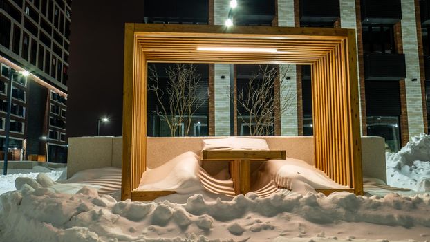 Benches and tables are covered with snow after a winter storm in the courtyard of a house in Moscow. evening shooting. color