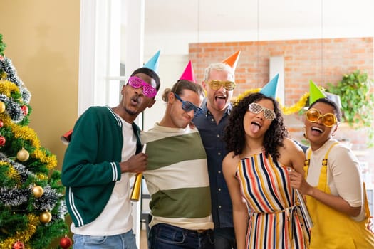 Group of happy diverse female and male friends with whistles and colorful hats celebrating new year. new year, festivities, celebrating at home with friends.