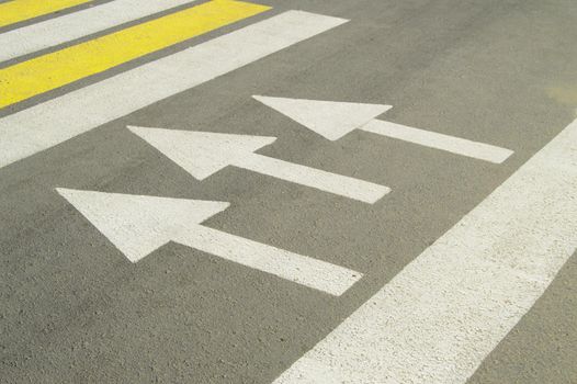 Asphalt road with arrow sign shows the direction of movement.