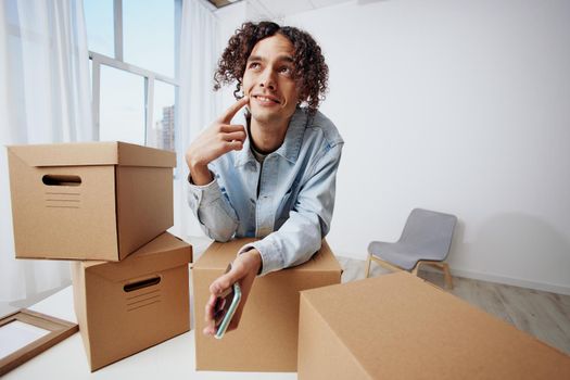 portrait of a man cardboard boxes in the room unpacking with phone sorting things out. High quality photo