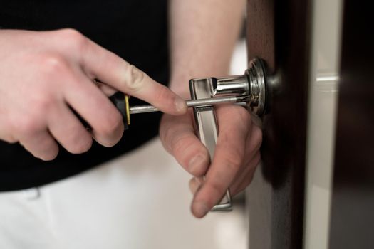 A man installs a handle on a wooden door