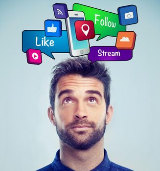 Studio shot of a handsome young man looking up at social media bubbles.