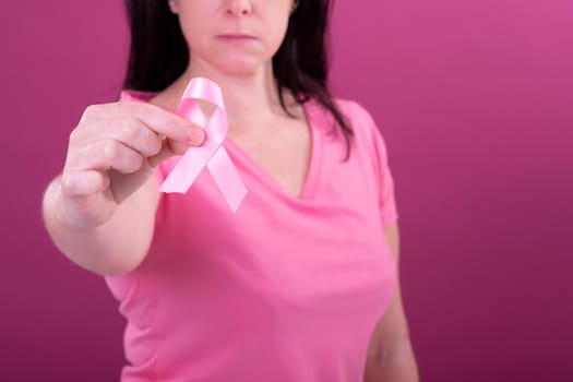 Midsection of caucasian woman in pink tshirt holding pink ribbon. breast cancer positive awareness campaign concept digitally generated video.