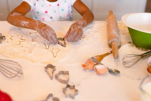 Hands of african american messy girl baking in kitchen. baking and cooking, childhood and leisure time at home.