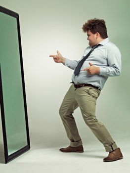 Shot of an excited overweight man celebrating while looking in a mirror.