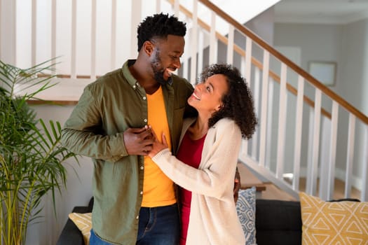 Happy african american couple hugging and looking at camera. family time, leisure and spending time at home.