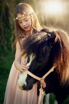 Shot of a cute little girl playing with her pony outside.