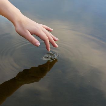 Cropped shot of a finger touching water to form ripples.
