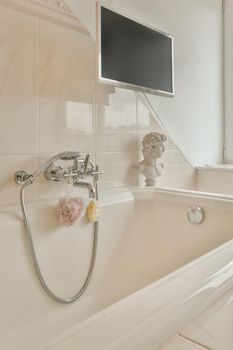 Ceramic bathtub with monitor decorated with bathroom accessories in a modern house