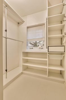 A storage room with a lot of shelves in a white design, a small window in a cozy house