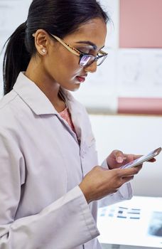Cropped shot of a young female dentist texting on her cellphone in her office.