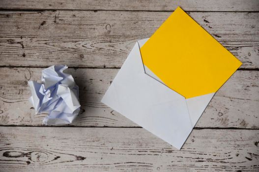 Top view of empty envelope with crumpled paper and wooden table background. Copy space