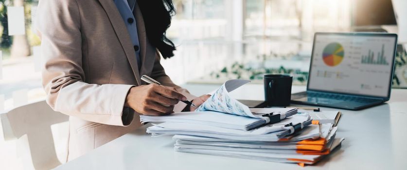 Accounting planning budget concept : Business woman offices working for arranging documents unfinished stack of document papers with pen.