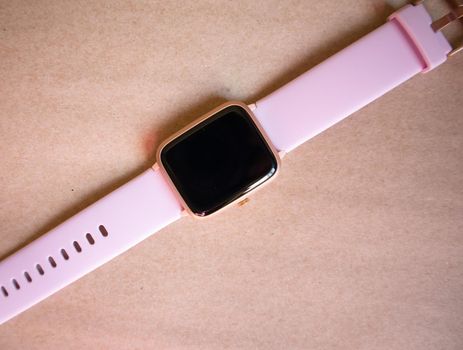 Wireless Smart Watch with Pink Strap Isolated on Brown kraft Paper Background.