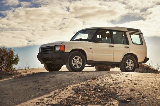 Shot of a heavy duty 4x4 driving along some sand dunes.