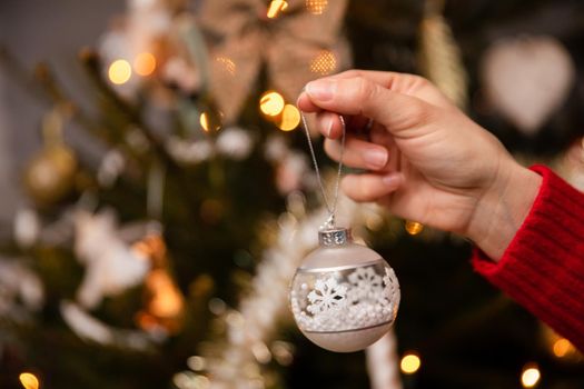 A woman's hand hangs a Christmas tree bauble to decorate the tree according to tradition in Poland. An annual Christmas ritual.