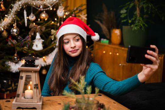 A happy and smiling teenager takes a selfie with her cell phone during the Christmas season.