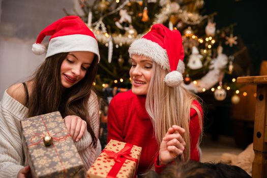 A happy and smiling mother and daughter, lying on the carpet with Christmas presents in their hands.