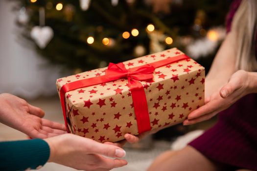 A wrapped gift given from hand to hand at Christmas time. Women's hands. The tradition of the world in Poland.