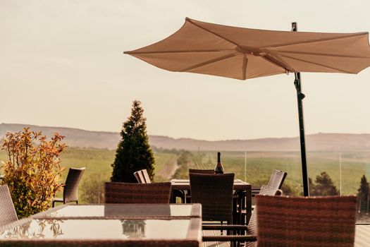 Empty tables in a street cafe overlooking mountains and trees. Sun umbrellas