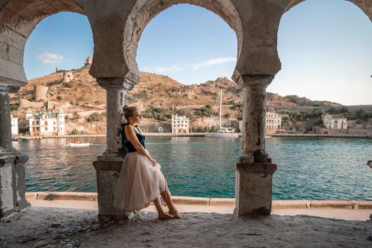 Side view portrait of a relaxed woman breathing fresh air at the seaside. She stands near the old column