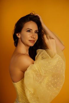 Profile portrait of a beautiful middle-aged woman in a yellow dress, her hair pulled up against a yellow background.