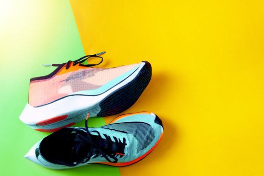 Blue and orange running shoes on color floor