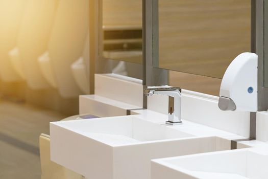 Toilet sink for wash hand with soap drop on blur urinal background