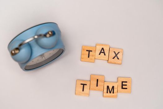 Close-up of alarm clock next to tax time concept on chalkboard.