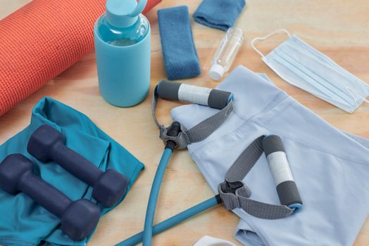 Studio shot of a variety of workout equipment and PPE on a wooden floor.