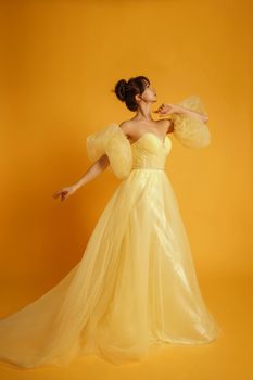 Profile portrait of a beautiful middle-aged woman in a yellow dress, her hair pulled up against a yellow background.