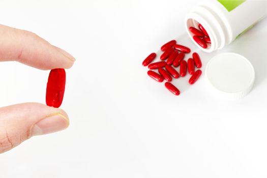 finger hold red pill medicine with bottle