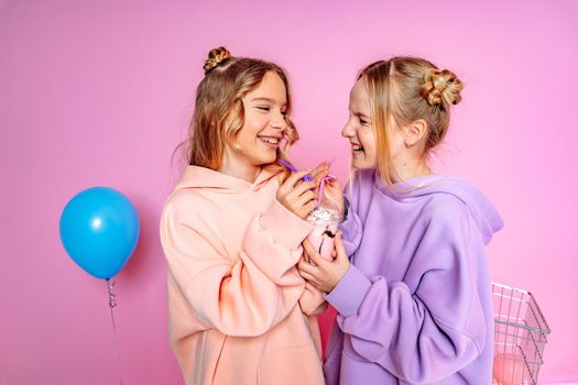 Two beautiful attractive funny joyful cheerful relaxed carefree girls dressed in casual fashion clothes isolated on hot pink background.