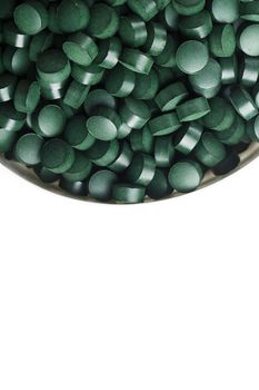 spirulina and chlorella tablets on the light background. green tablets in the small bawl