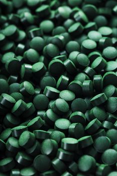 Dark Green round tablets of organic spirulina as a texture background in full screen