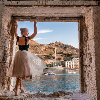 Side view portrait of a relaxed woman breathing fresh air at the seaside. She stands on the window in the old building