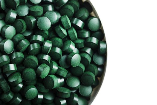 spirulina and chlorella tablets on the light background. green tablets in the small bawl