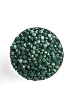 spirulina and chlorella tablets on the light background. green tablets in the small bawl